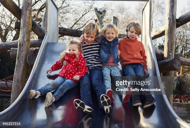 children on a slide in the park - いとこ ストックフォトと画像