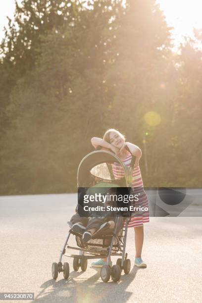 girl pushing boy in stroller - baby brother stock pictures, royalty-free photos & images