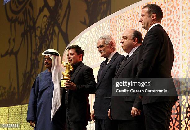 Brillante Mendoza with the Muhr AsiaAfrica Feature Best Film award for Lola onstage with DIFF Chairman Abdulhamid Juma actor Omar Sharif and guests...