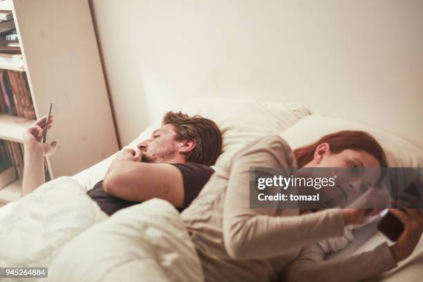 couple in bet separated by smart phones - infidelity stock pictures, royalty-free photos & images