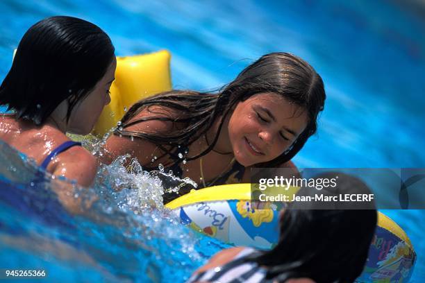 ENFANTS JOUANT DANS UNE PISCINE.