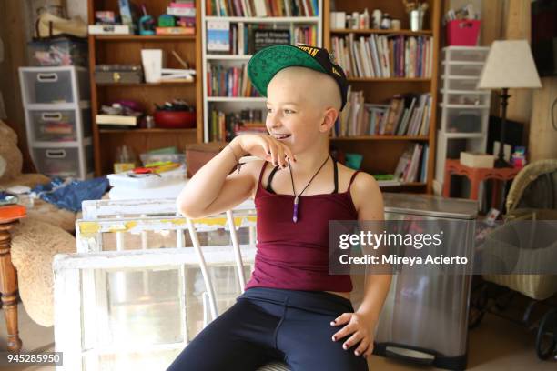 portrait of young girl with cancer, laughing, wearing a baseball hat and and tank top. - cancer portrait stock pictures, royalty-free photos & images