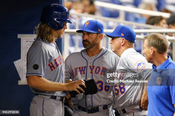 Noah Syndergaard of the New York Mets talks with manager Mickey Callaway and pitching coach Dave Eiland against the Miami Marlins at Marlins Park on...