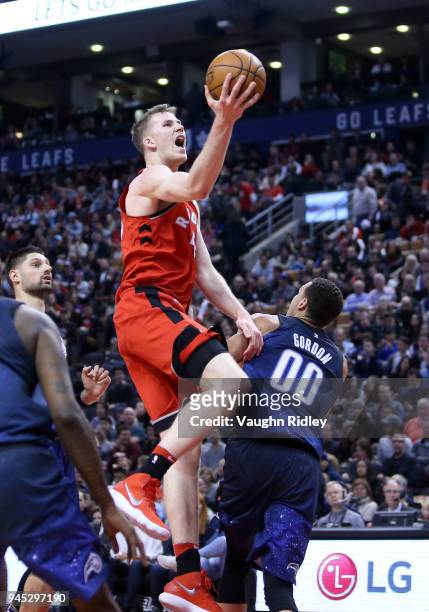Jakob Poeltl of the Toronto Raptors shoots the ball as Aaron Gordon of the Orlando Magic during the second half of an NBA game at Air Canada Centre...