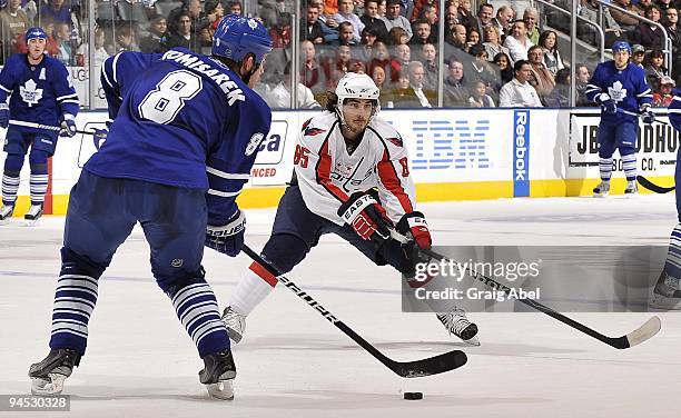 Mike Komisarek of the Toronto Maple Leafs looks to play the puck past the attacking Mathieu Perreault of the Washington Capitals during game action...