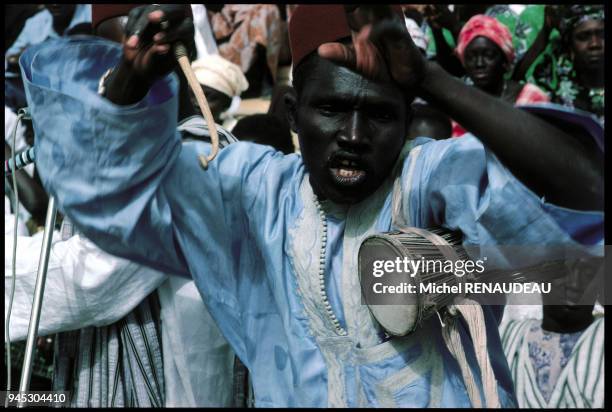 GRIOT SENEGALAIS JOUANT DU TAM-TAM D'AISSELLE.