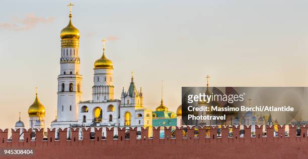 moscow kremlin, the walls and the onion golden domes of the ivan the great bell tower (really a church tower) on the left and, on the right, of the cathedral of the dormition - kremlin stock pictures, royalty-free photos & images