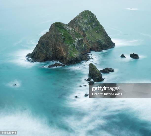 rocky island surrounded by dramatic soft-focus sea - softfocus stock-fotos und bilder