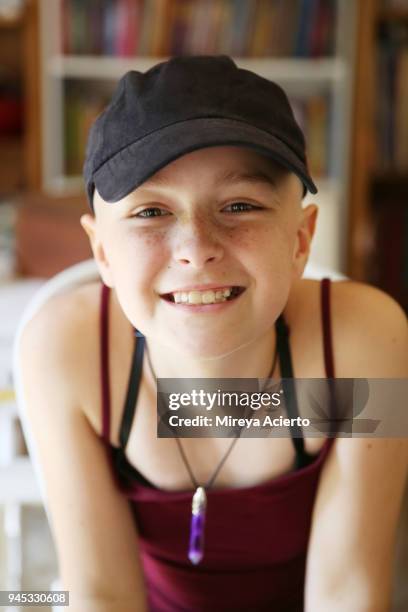 portrait of young girl with cancer, smiling into camera, wearing a baseball hat and tank top. - baseballmütze stock-fotos und bilder