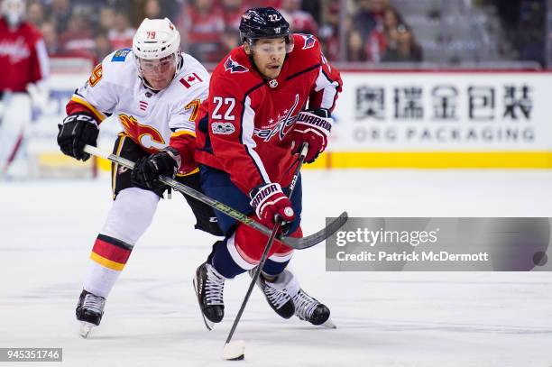 Madison Bowey of the Washington Capitals and Micheal Ferland of the Calgary Flames battle for the puck in the third period at Capital One Arena on...