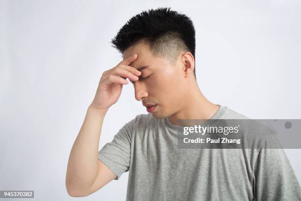 youngman annoyance, pinching nose, against white background - pinching nose stockfoto's en -beelden