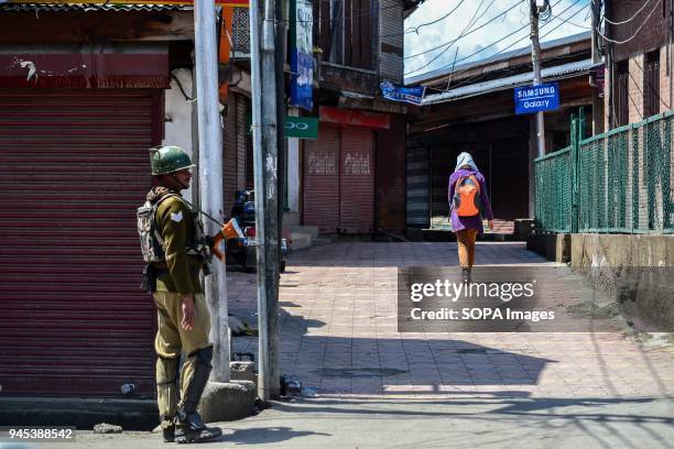 Kashmiri student walks past an Indian paramilitary trooper standing guard during restrictions in Srinagar, Indian administered Kashmir. As Muslim...