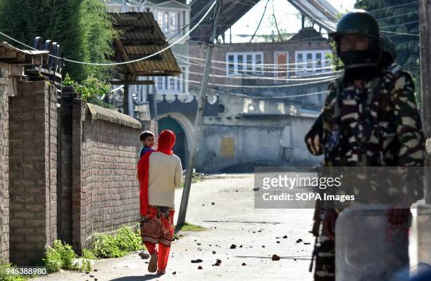 Woman carrying her child walks past an Indian policeman during clashes in Srinagar, Indian administered Kashmir. As Muslim majority areas of Kashmir...
