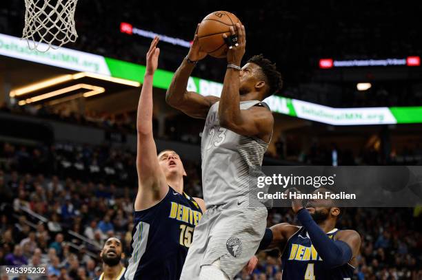 Jimmy Butler of the Minnesota Timberwolves shoots the ball against Nikola Jokic and Paul Millsap of the Denver Nuggets during the first quarter of...