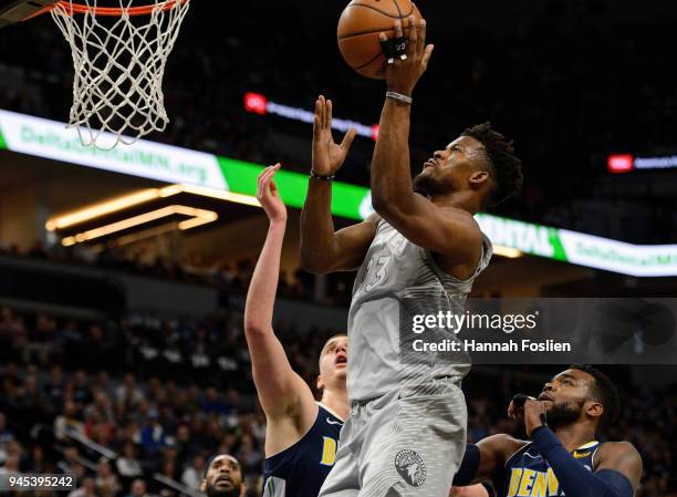 Jimmy Butler of the Minnesota Timberwolves shoots the ball against Nikola Jokic and Paul Millsap of the Denver Nuggets during the first quarter of...