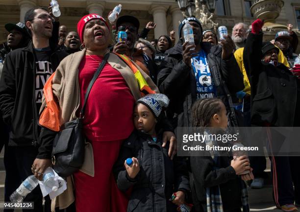 Claudia Perkins of Flint, Michigan, joins in a chant as her grandchildren, Laila Halford, left and DeAngelo Perkins, right watch during a protest on...