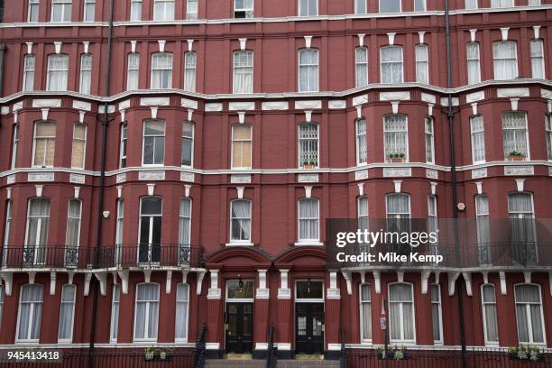 Mansion style building painted ox blood red in Marylebone in London, England, United Kingdom. A mansion block refers to a block of flats or...
