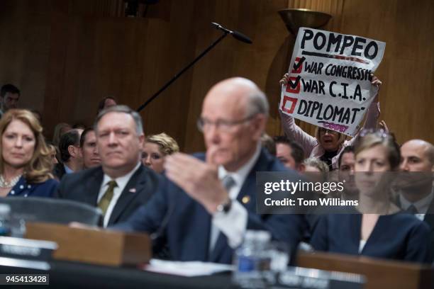 Protester from Code Pink who opposes CIA Director Mike Pompeo, left, nominee for secretary of state, holds a sign during Pompeo's Senate Foreign...