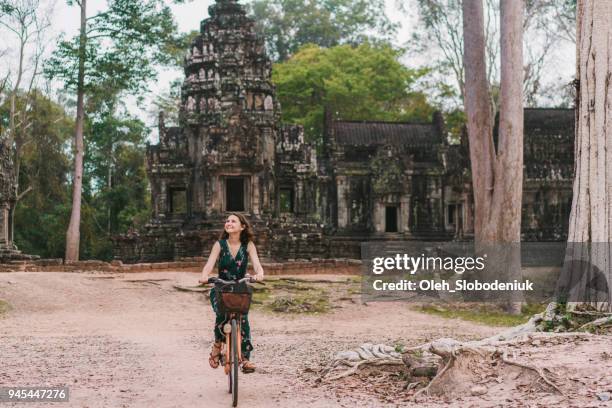 young caucasian woman riding  bicycle  in angkor wat - angkor wat stock pictures, royalty-free photos & images