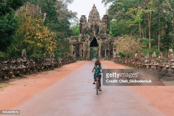 young caucasian woman riding  bicycle  in angkor wat - cambodia stock pictures, royalty-free photos & images