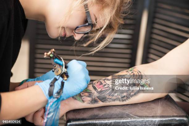 woman making tattoo in salon - tatoo foto e immagini stock
