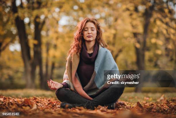 giovane donna che medita in posizione lotus al parco. - ambientazione tranquilla foto e immagini stock