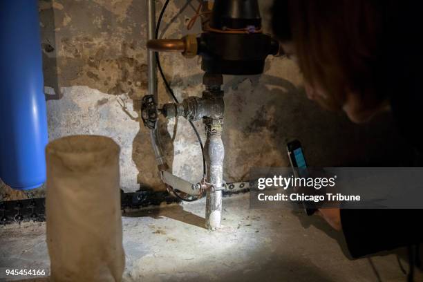 Jenny Abrahamian shines on a light on the newer plumbing connected to older, lead plumbing at her home on Wednesday, April 4 in Chicago, Ill. After...