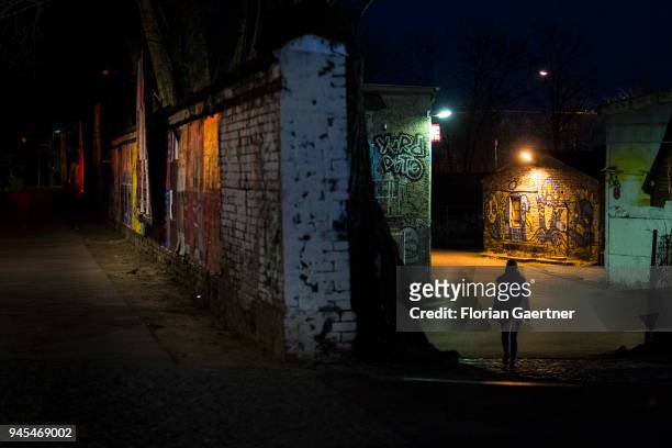 Woman runs alone at night along a barren illuminated street on April 06, 2018 in Berlin, Germany.