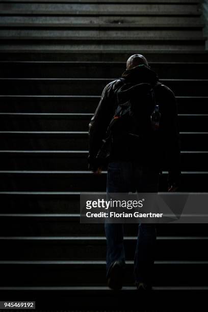 Bald man walks up a flight of stairs in the dark on April 06, 2018 in Berlin, Germany.