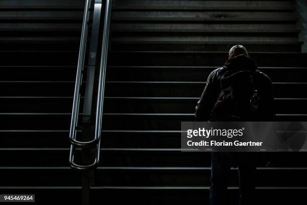 Bald man walks up a flight of stairs in the dark on April 06, 2018 in Berlin, Germany.