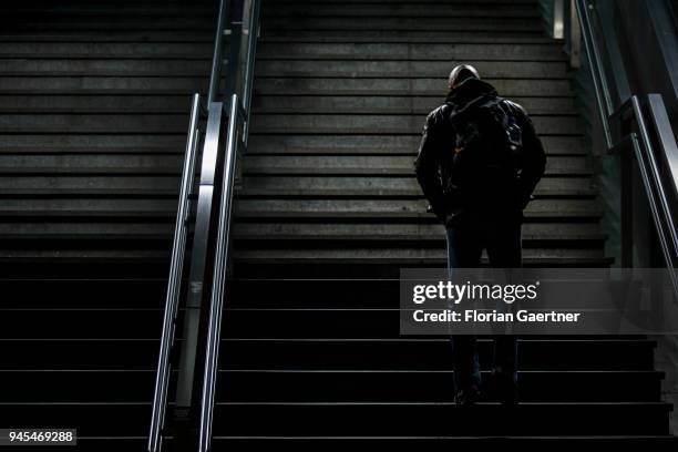 Bald man walks up a flight of stairs in the dark on April 06, 2018 in Berlin, Germany.