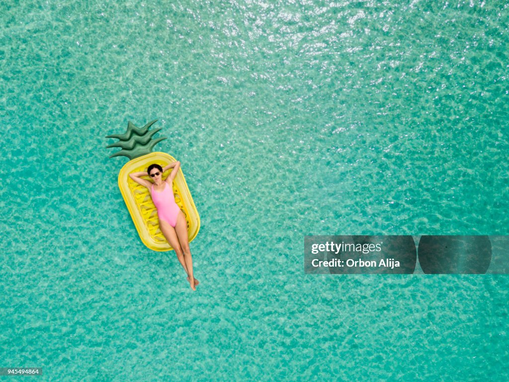 Carefree woman on inflatable pineapple