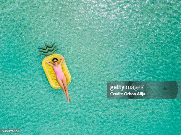 carefree woman on inflatable pineapple - lying on back photos stock pictures, royalty-free photos & images