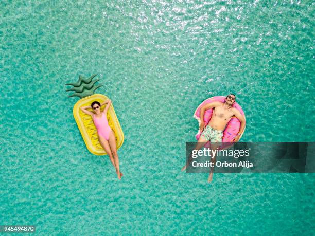 couple relaxing at the sea - rubber ring stock pictures, royalty-free photos & images