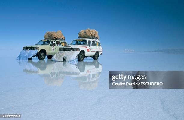 Two four-wheel drive cars reflected in the water that covers the salty lake of Uyuni. Deux 4X4 se refl?tent sur le salar de Uyuni recouvert d'eau.
