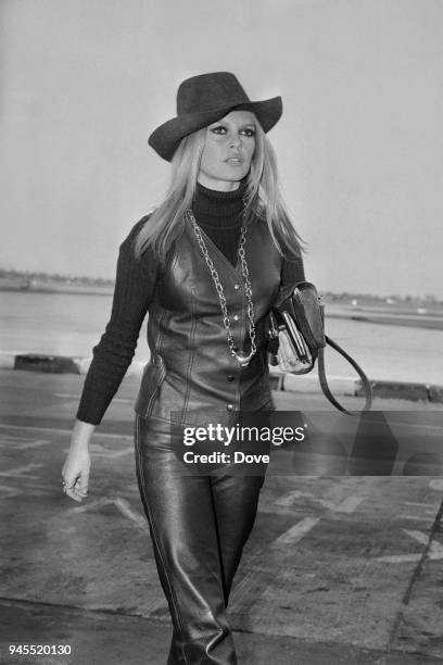 French actress, singer and fashion model Brigitte Bardot wearing leather waistcoat, high-collar shirt, leather pants and cowboy hat, Heathrow...