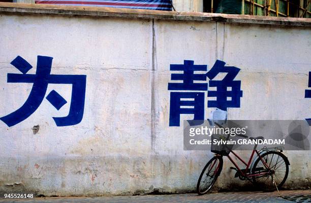 CHINA.SHANGHAI. STREET SCENE IN THE OLD TOWN. IDEOGRAMS PAINTED ON WALL AND BICYCLES CHINE.SHANGHAI. SCENE DE RUE DANS LA VILLE ANCIENNE. IDEOGRAMMES...