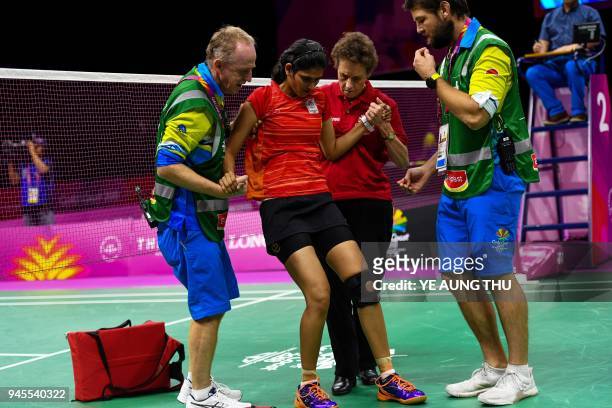 India's Ruthvika Gadde is being helped up by the medical team after sustaining an injury against Scotland's Kirsty Gilmour during their badminton...