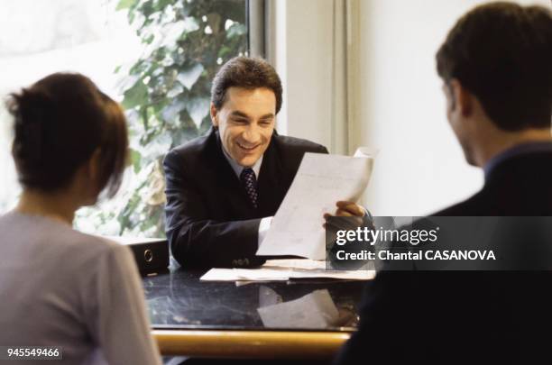 Jeune couple signant un contrat dans une banque pour un pr?t immobilier.