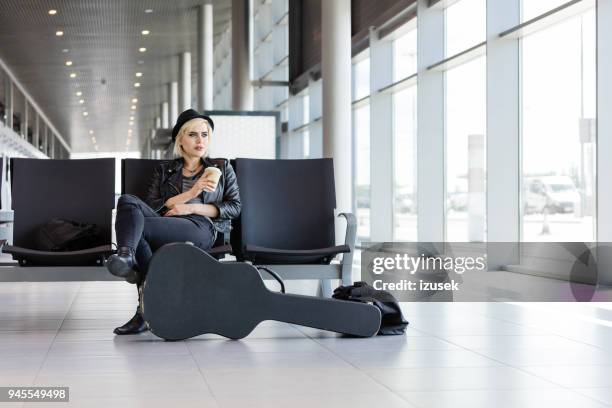 prachtige vrouwelijke musicus te wachten in de luchthaven lounge - passenger muzikant stockfoto's en -beelden