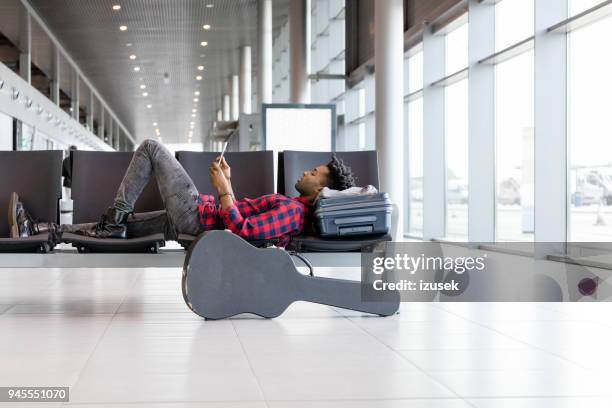 afrikaanse man vlucht wacht bij luchthaven lounge - passenger muzikant stockfoto's en -beelden