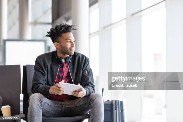 jonge afrikaanse man vlucht in de luchthaventerminal wacht - airport hipster travel stockfoto's en -beelden