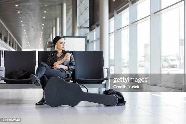 funky jonge vrouw te wachten in de luchthaven lounge - passenger muzikant stockfoto's en -beelden