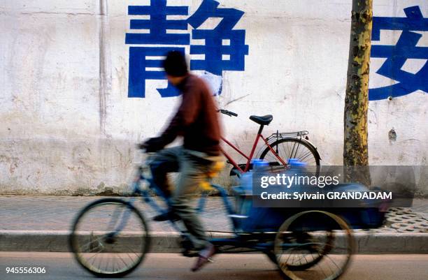 CHINA.SHANGHAI. STREET SCENE IN THE OLD TOWN. IDEOGRAMS PAINTED ON WALL AND BICYCLES CHINE.SHANGHAI. SCENE DE RUE DANS LA VILLE ANCIENNE. IDEOGRAMMES...