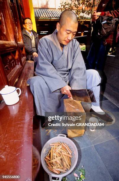 CHINA.SHANGHAI. THE JADE BUDDHA BUDDHIST TEMPLE. MONK PREPARING SMALL SANDAL WOOD STICKS FOR BURNING AS INCENSE CHINE.SHANGHAI. LE TEMPLE DU BOUDDHA...