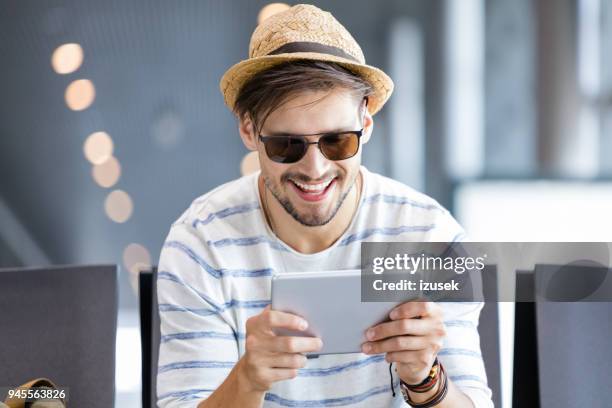 lachende mannelijke passagiers met behulp van digitale tablet in luchthaven lounge - male airport stockfoto's en -beelden