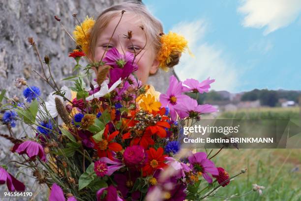 Une fille de 5 ans tient un bouquet de fleurs des champs.