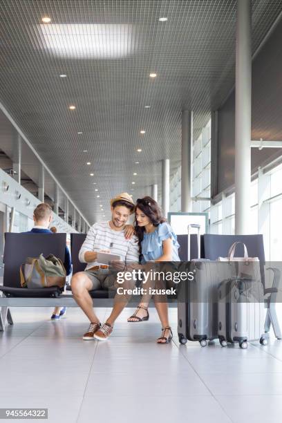 met behulp van digitale tablet in luchthaven lounge (echt) paar - airport couple stockfoto's en -beelden