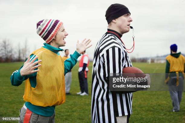 caucasian woman team member arguing with a referee while playing non-contact flag football. - american football referee stockfoto's en -beelden