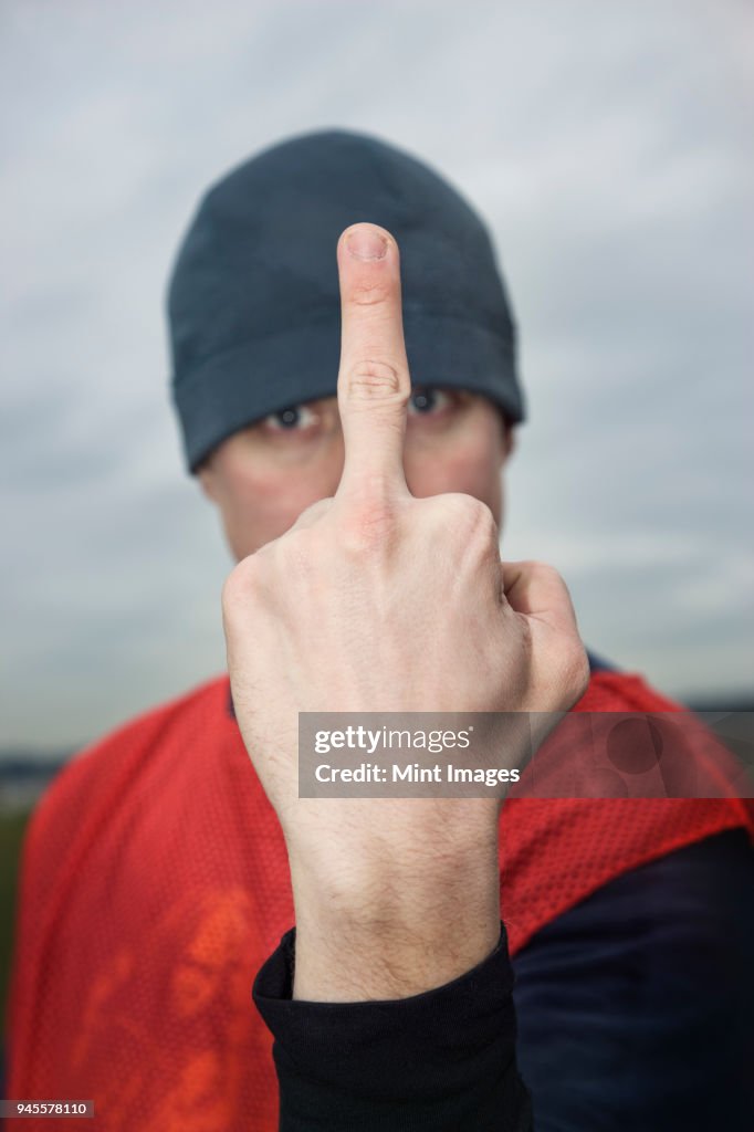 Caucasian man giving the viewer the finger as an obscene gesture.